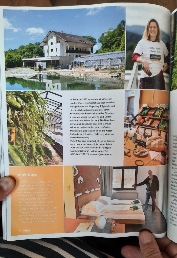 Eine aufgeschlagene Zeitschrift zeigt mehrere Fotos und Text. Oben links ist ein großes Gebäude mit Teich und Gewächshaus zu sehen. Daneben steht eine Person im weißen T-Shirt mit der Aufschrift „VinzRast“. Unten links hängen grüne Pflanzen in einem Gewächshaus. Rechts daneben ist ein Regal mit frischem Gemüse und ein Tisch mit Lebensmitteln. Unten rechts befindet sich ein Zimmer mit zwei Betten, einem Fenster und einer Person, die auf die Einrichtung zeigt. In der Mitte steht ein Text über das Projekt „VinzRast am Land“.
