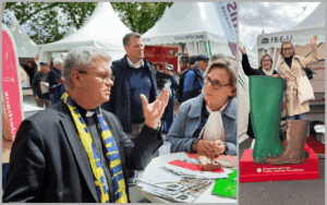 Menschen an einem Informationsstand auf einem Außenevent. Eine Person im Vordergrund spricht gestikulierend mit einer weiteren Person an einem Tisch mit Flyern. Im Hintergrund stehen Zelte mit der Aufschrift „Caritas“. Rechts: Zwei Personen stehen in übergroßen Gummistiefeln auf einem Podest mit der Beschriftung „Zusammen geht was. Caritas verbindet Generationen“.