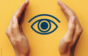 Zwei Hände bilden links und rechts einen schützenden Rahmen um ein stilisiertes Auge in dunkelblauer Farbe. Hintergrund ist ein einfarbiger gelber Farbton. Das Motiv visualisiert Schutz, Sehen und Augengesundheit.